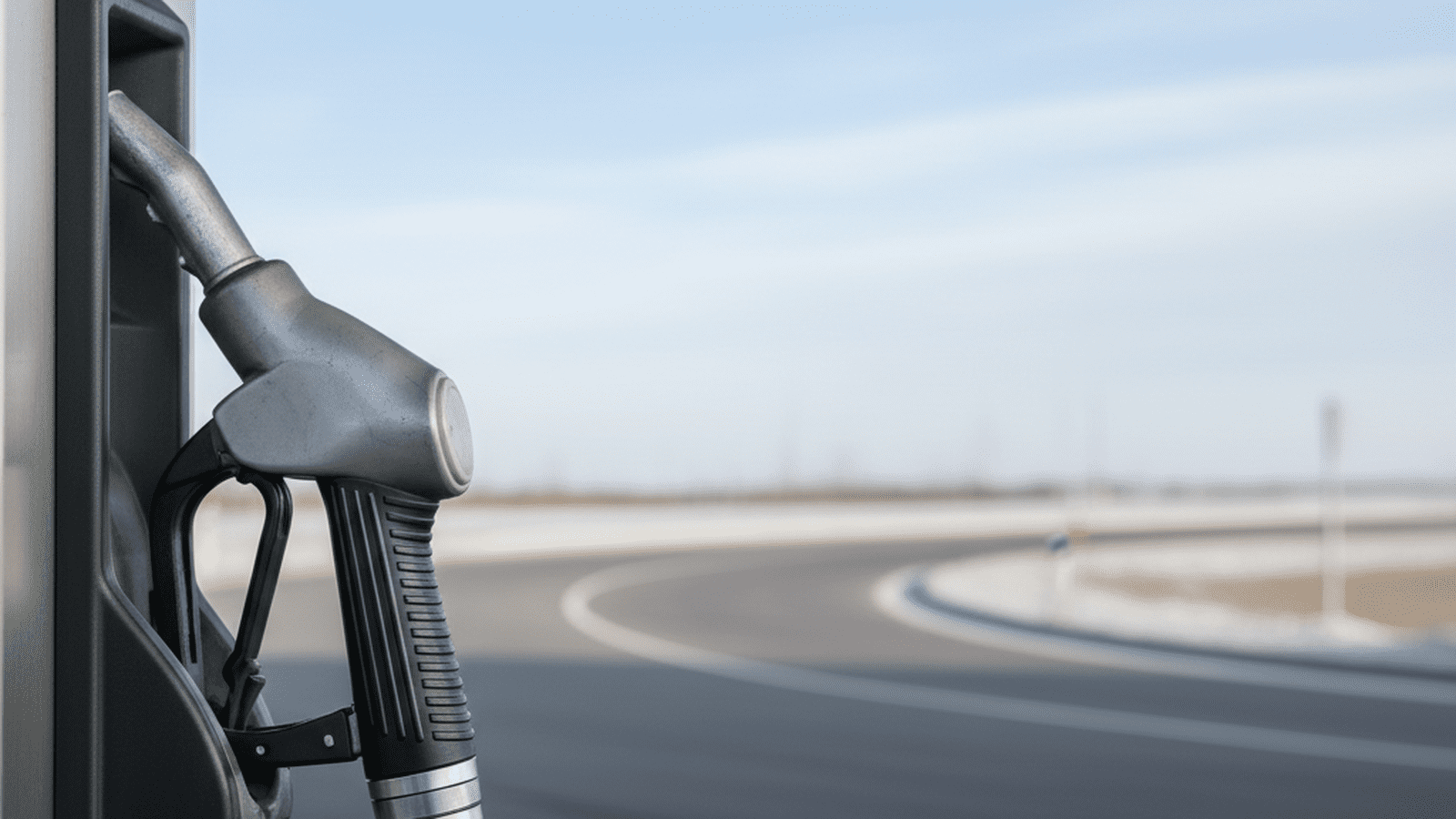 A close-up of a gasoline pump handle at a service station during a clear winter day.