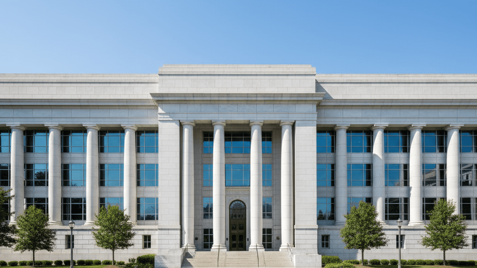 A large government building stands under a clear blue sky, representing stability and official oversight.