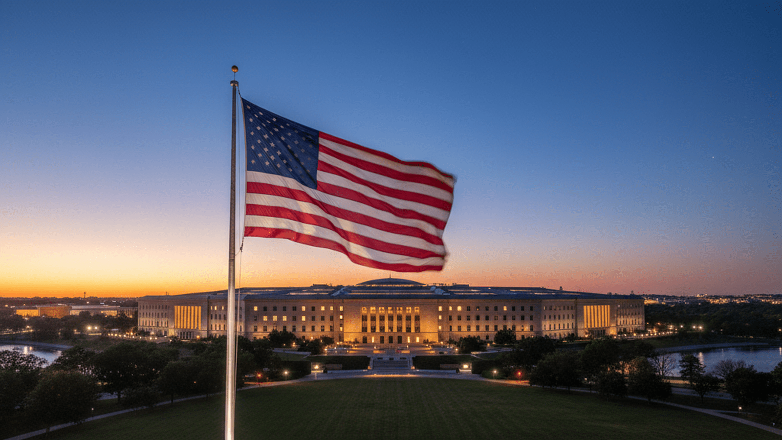 The Pentagon building stands under a clear evening sky with the American flag in view.