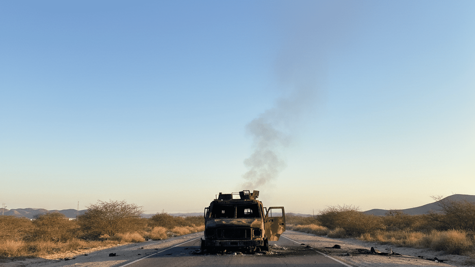 A charred vehicle sits on a quiet road in Jalisco, Mexico, following a military operation against a cartel leader.