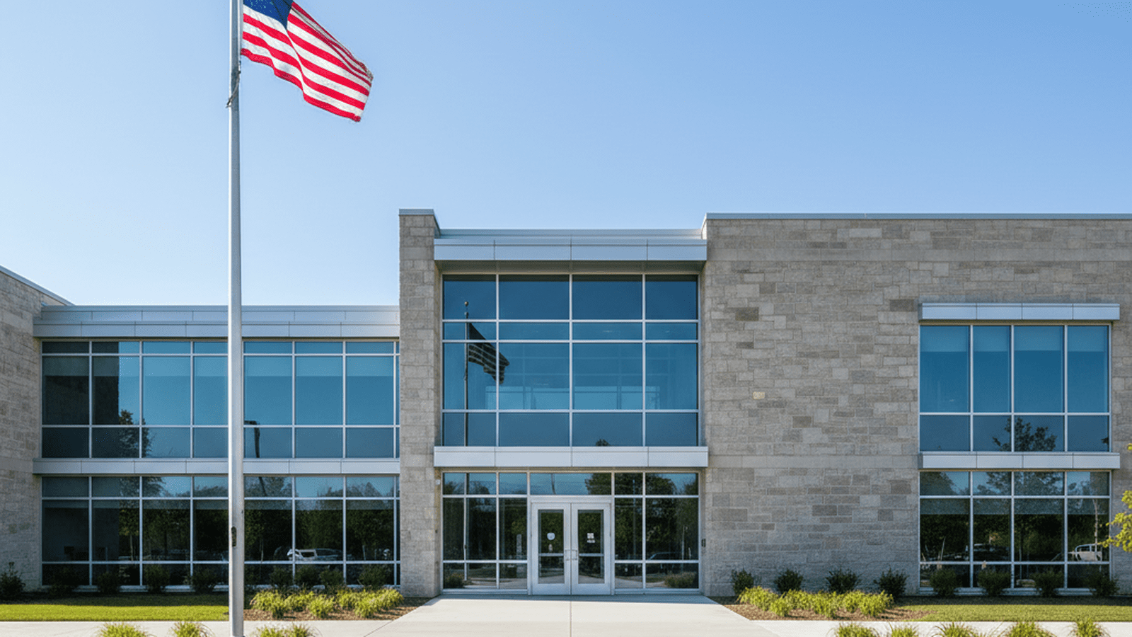 The exterior of a modern stone and glass county courthouse in Michigan under a clear blue sky.