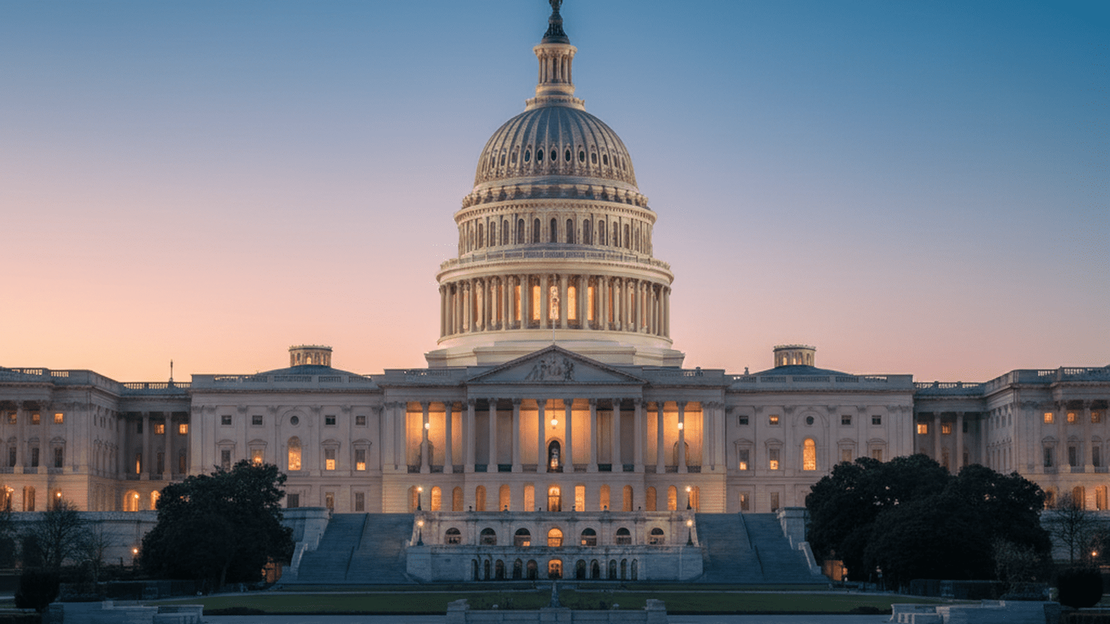 The United States Capitol building stands illuminated at dusk under a clear sky.