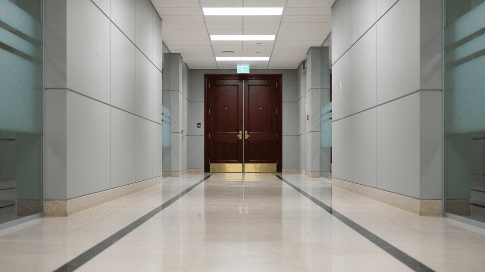 A quiet, brightly lit hallway in a federal government building with a closed office door.