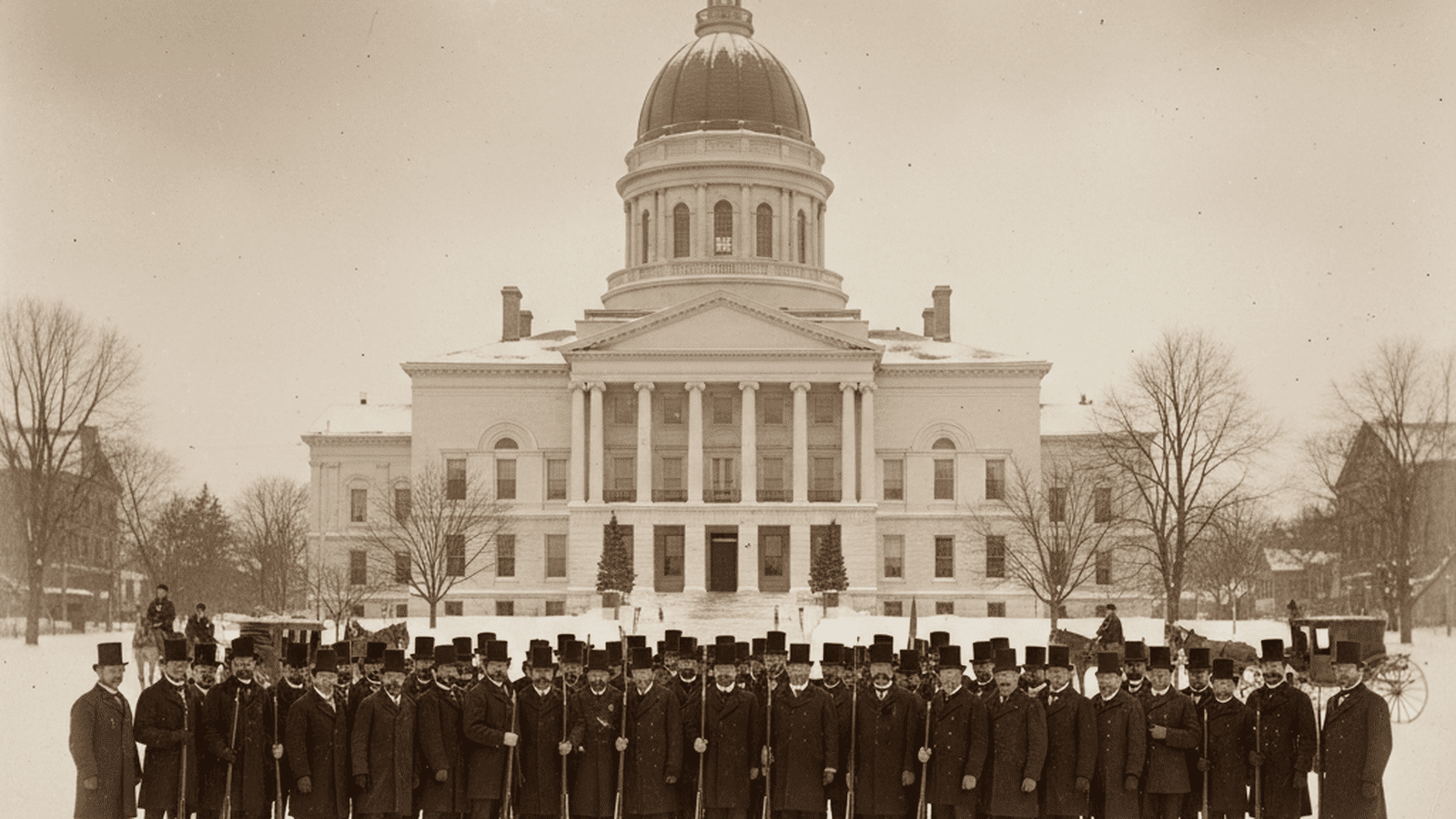 A historical monochrome photo of men in 19th-century attire gathered outside the Maine State House in the snow.