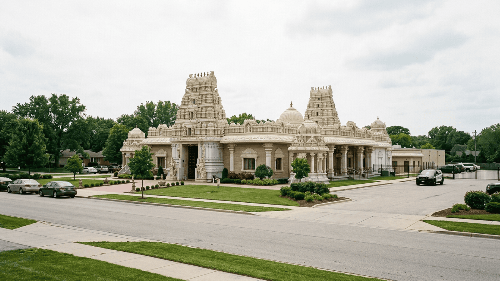 A Hindu temple in Aurora, Illinois, stands beside a quiet street with a police vehicle in the distance.