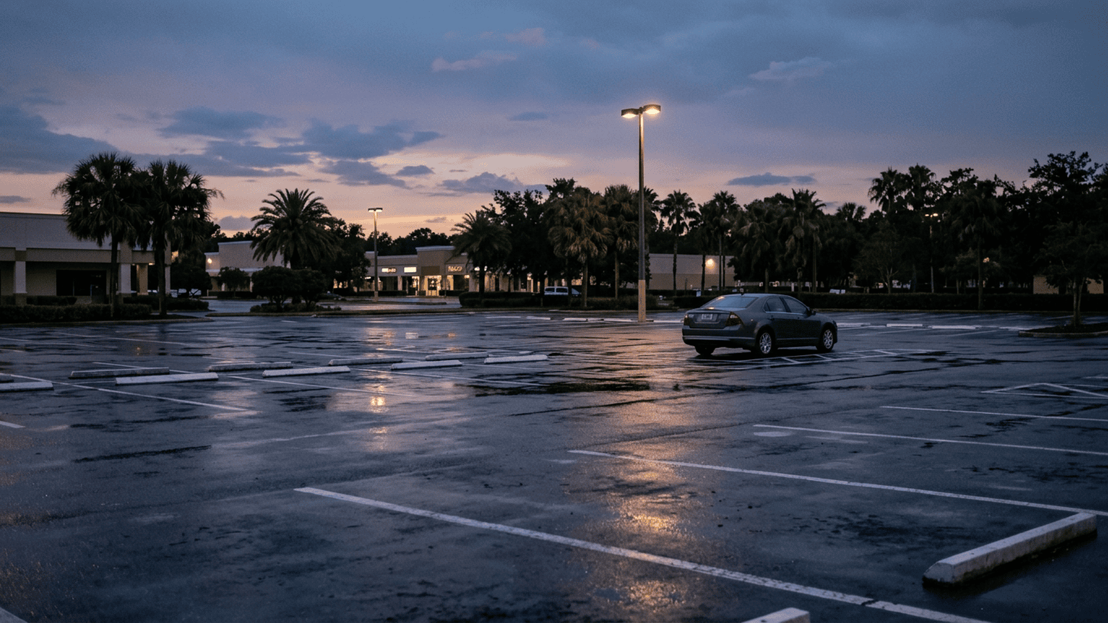 An empty Orlando parking lot at dusk with a vehicle in the distance.