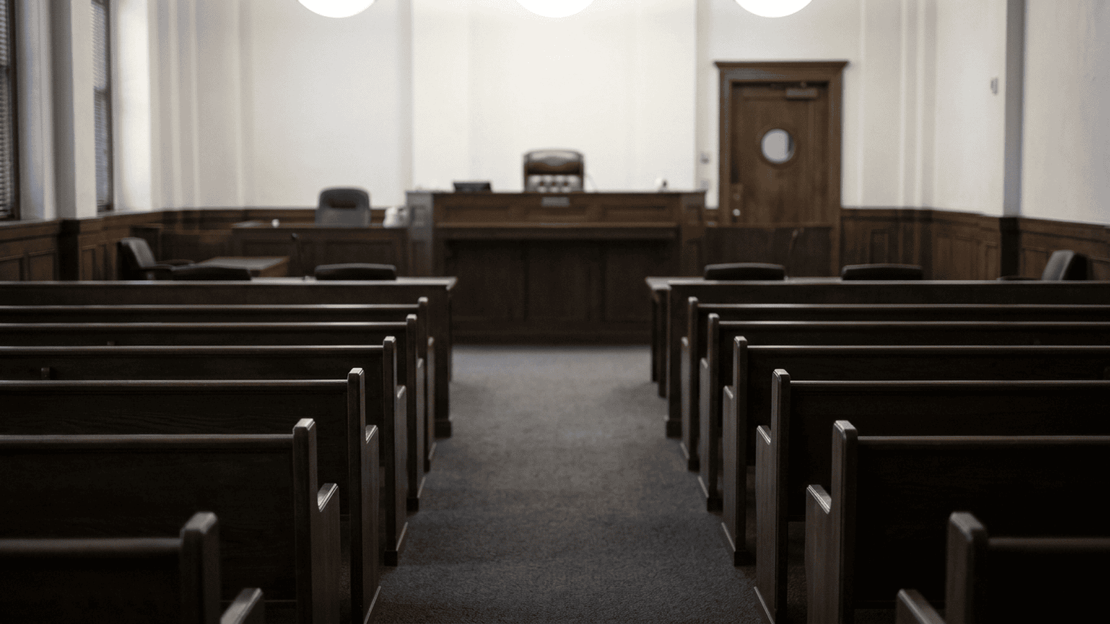 An empty courtroom in Las Vegas with the judge’s bench visible beyond rows of seats.