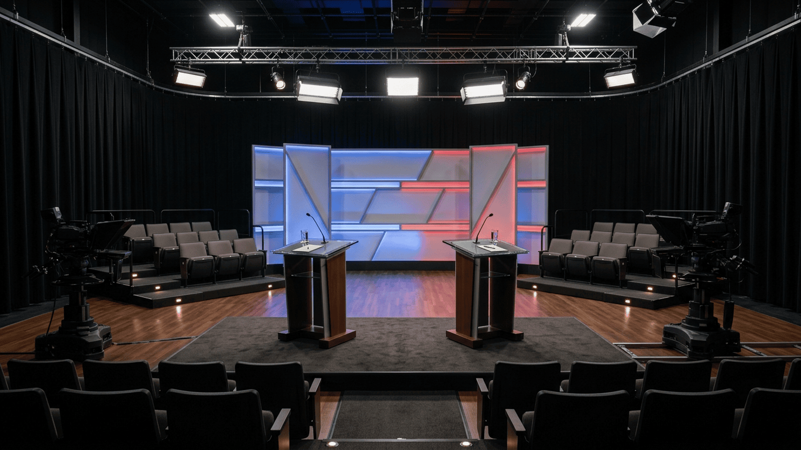 An empty television debate stage with two lecterns under studio lights.