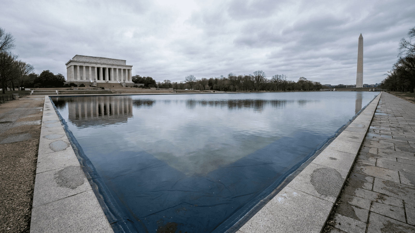 The Reflecting Pool in Washington, D.C., viewed from its stone edge on an overcast day.