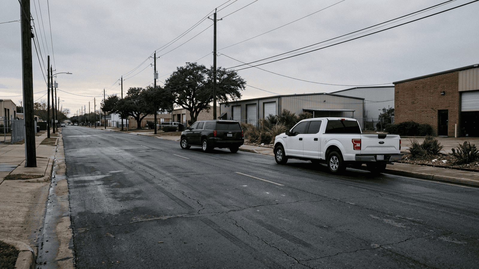 A white pickup and dark SUV are parked on a Houston street near a commercial area.