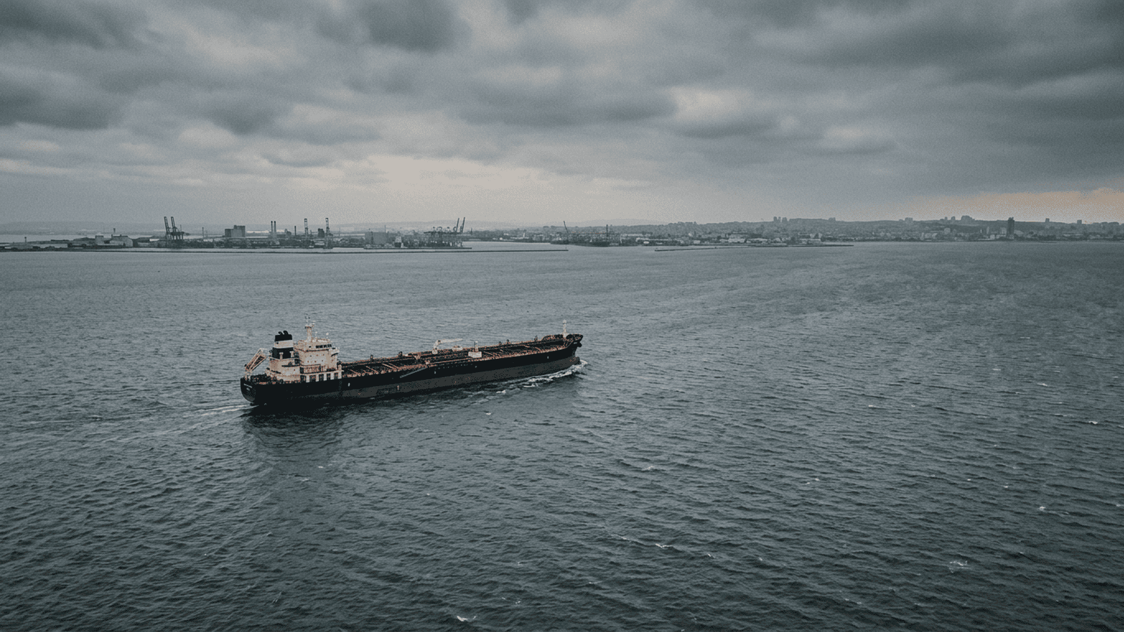 An oil tanker travels across a gray sea under an overcast sky.